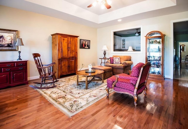  - living room featuring a ceiling fan, wood finished floors, a raised ceiling, and baseboards