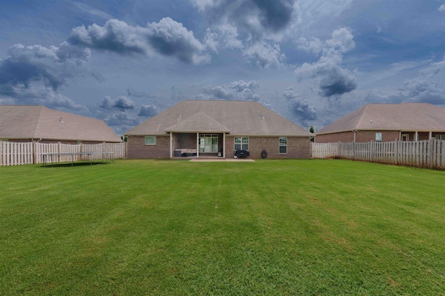  - rear view of property featuring a trampoline, a patio, a fenced backyard, and brick siding