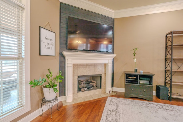 living room featuring hardwood / wood-style flooring, ornamental molding, and a tile fireplace