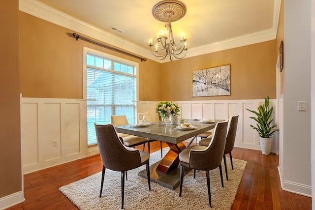  - dining area with a decorative wall, a chandelier, ornamental molding, wainscoting, and dark wood finished floors