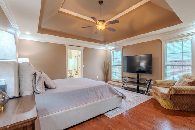 bedroom featuring wood-type flooring, ornamental molding, a raised ceiling, and ceiling fan