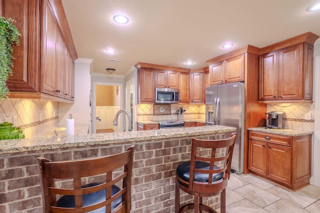 kitchen with stainless steel appliances, a kitchen breakfast bar, and light stone countertops