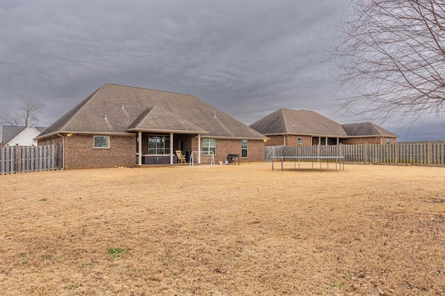 back of house with a yard and a trampoline