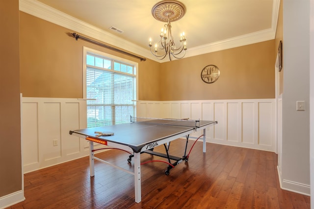 game room with an inviting chandelier, dark wood-type flooring, and ornamental molding