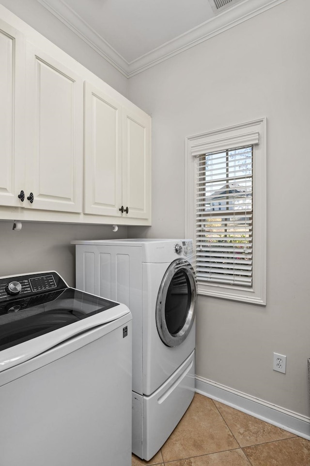 laundry room featuring cabinets, light tile patterned floors, washing machine and dryer, and ornamental molding