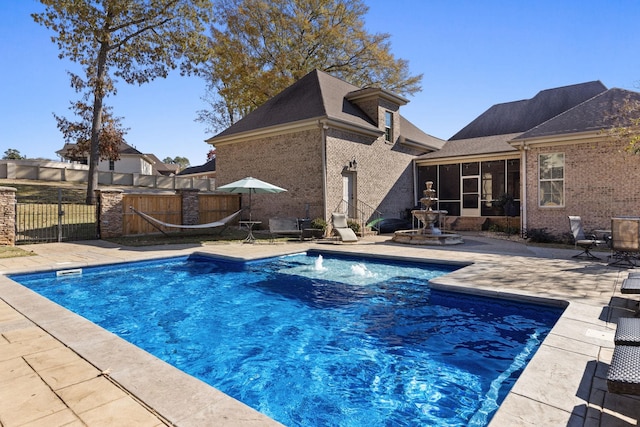 view of swimming pool with a sunroom and a patio area