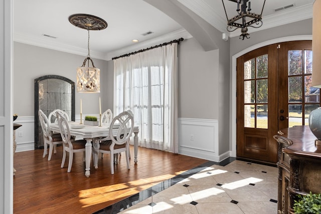 dining area featuring french doors, tile patterned floors, crown molding, and a notable chandelier