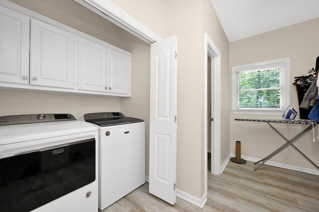 laundry room with washer and dryer, light hardwood / wood-style flooring, and cabinets