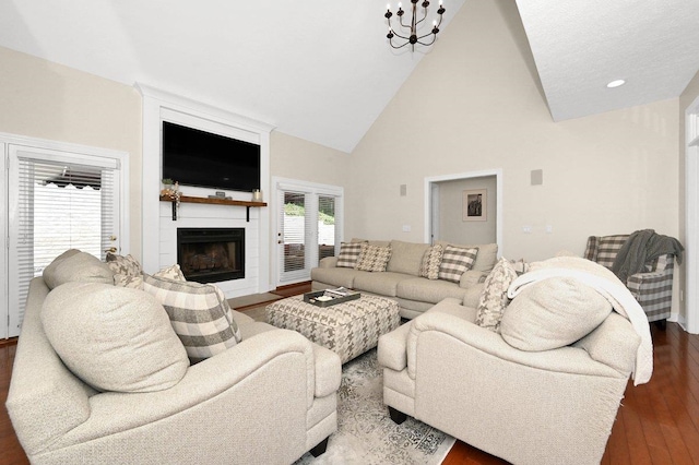 living room featuring a notable chandelier, a large fireplace, dark hardwood / wood-style flooring, and high vaulted ceiling