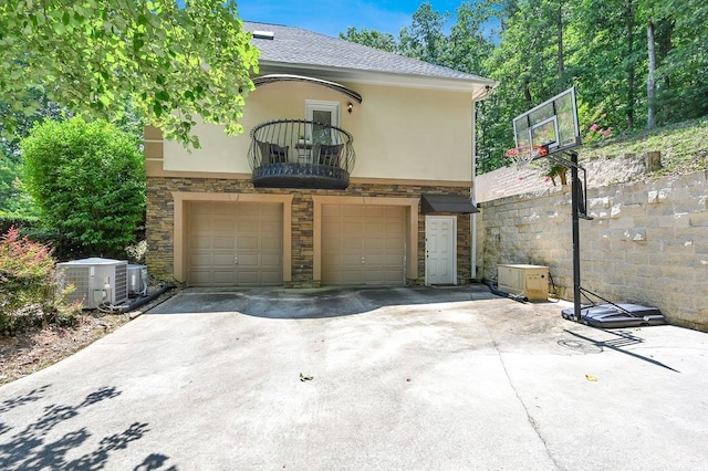 exterior space featuring central AC unit, a garage, and a balcony