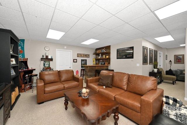 carpeted living room featuring a drop ceiling and bar