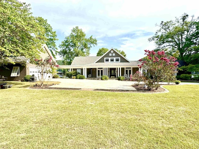 rear view of property with a lawn, covered porch, and a garage