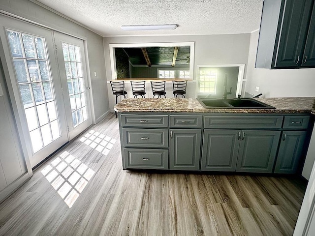  - kitchen featuring a peninsula, a textured ceiling, light wood finished floors, healthy amount of natural light, and gray cabinets