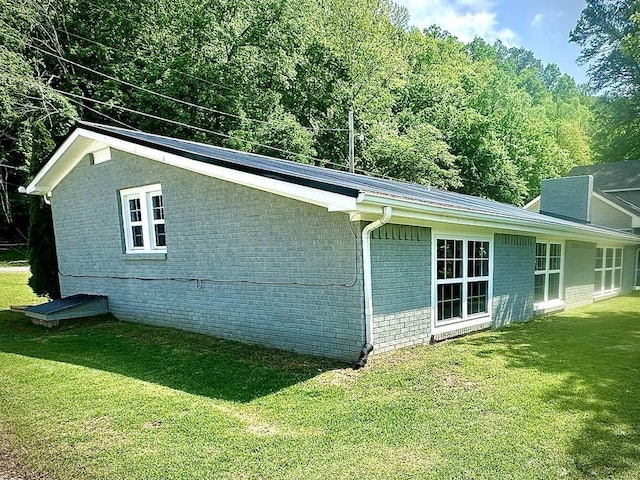  - view of side of property featuring a yard and brick siding