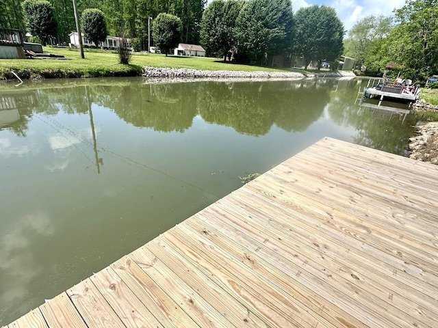  - dock area with a water view, a lawn, and view of scattered trees