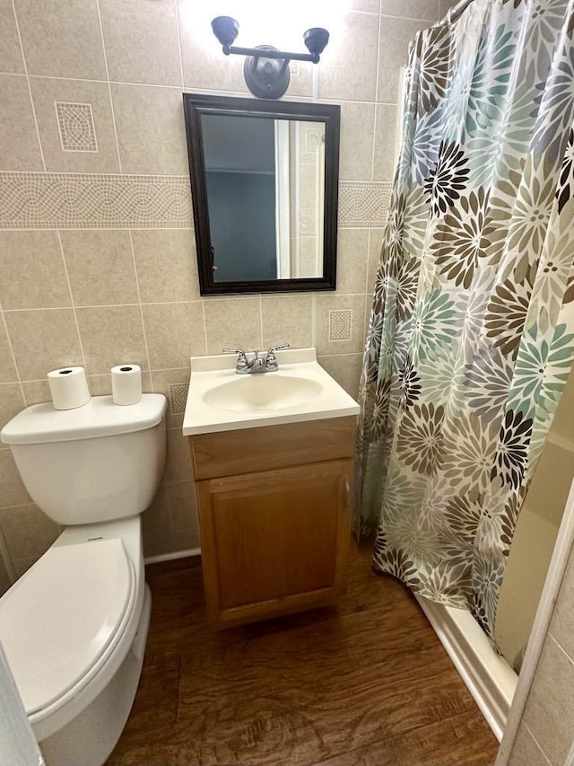  - bathroom featuring tile walls, vanity, toilet, a stall shower, and backsplash