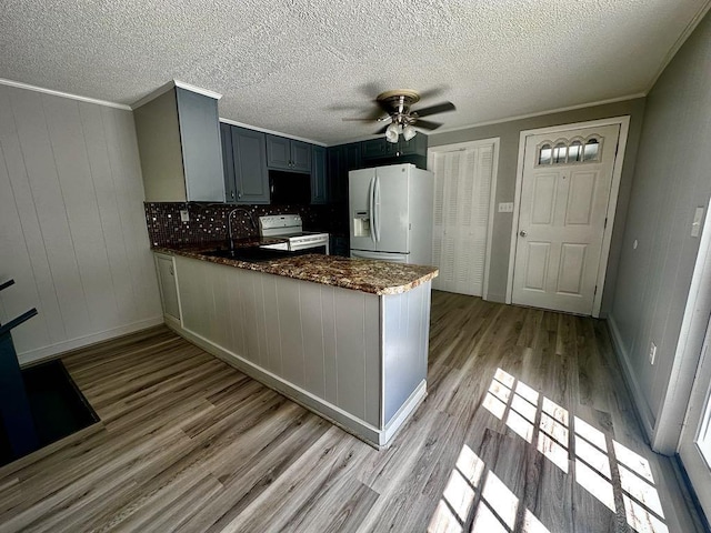  - kitchen with white appliances, a sink, light wood-type flooring, ceiling fan, and a peninsula