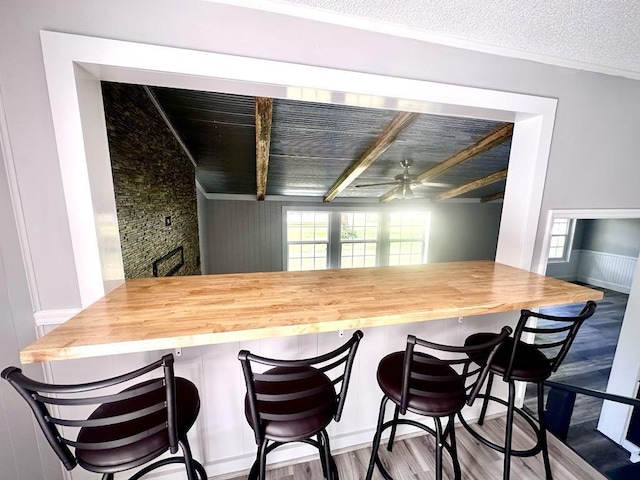  - kitchen featuring plenty of natural light, a ceiling fan, wood finished floors, and a breakfast bar area
