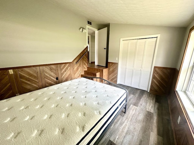 - bedroom featuring dark wood-type flooring, a closet, vaulted ceiling, and a wainscoted wall