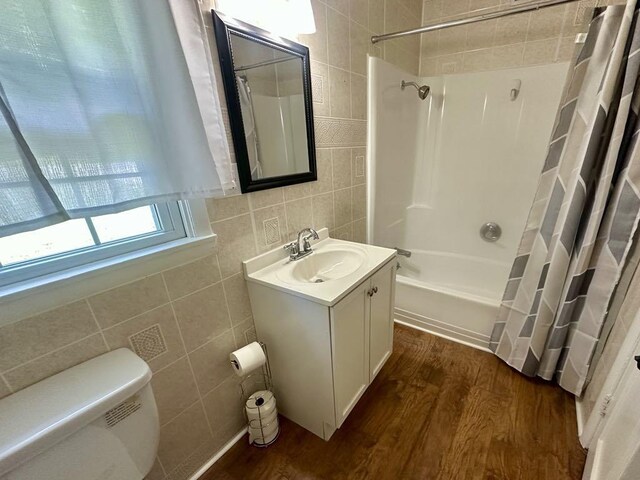  - full bathroom featuring tile walls, wood finished floors, shower / bath combo, vanity, and toilet