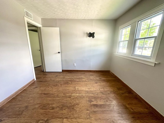  - unfurnished room with wood finished floors, a textured ceiling, and baseboards