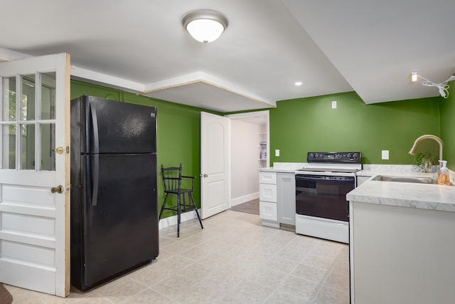 kitchen featuring white range with electric cooktop, black fridge, sink, and white cabinets