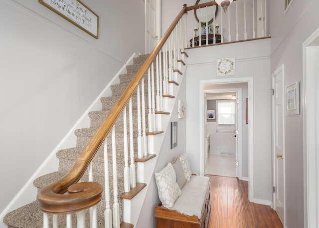 stairway featuring hardwood / wood-style floors and a towering ceiling