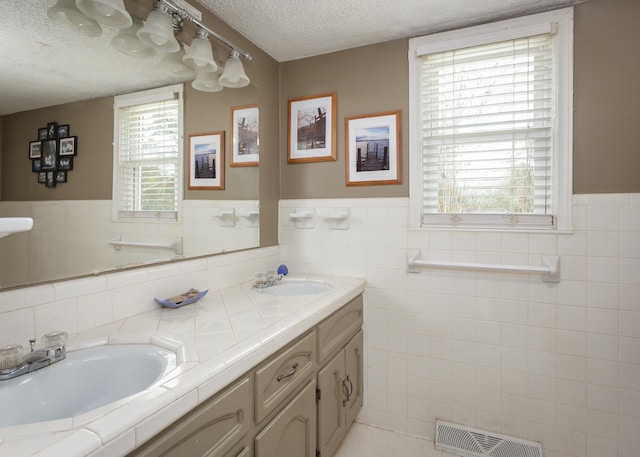 bathroom featuring tile patterned flooring, vanity, a healthy amount of sunlight, and a textured ceiling