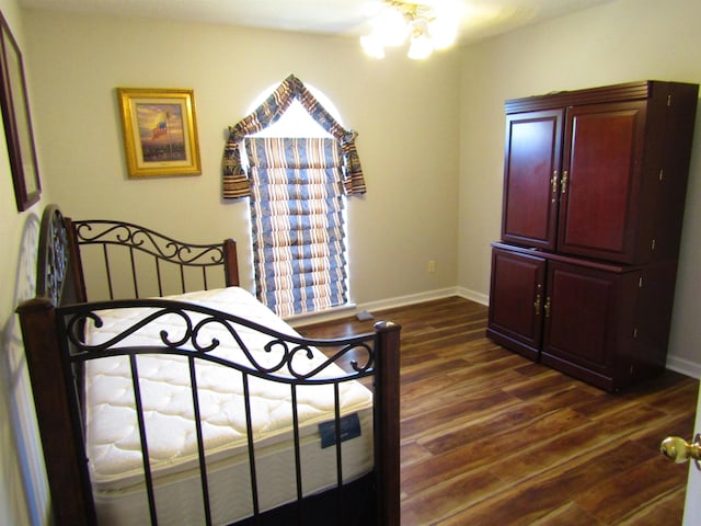 bedroom with dark hardwood / wood-style floors and an inviting chandelier