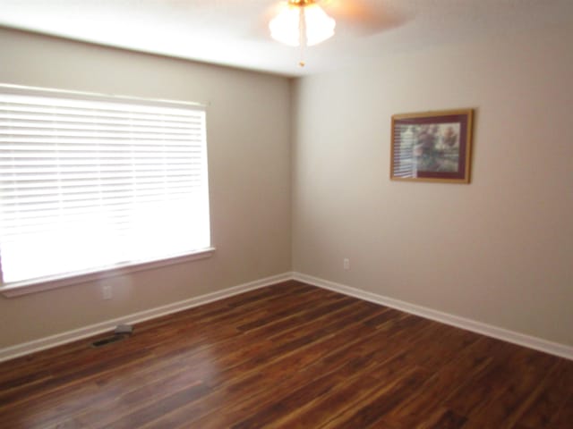 unfurnished room with plenty of natural light, ceiling fan, and dark wood-type flooring