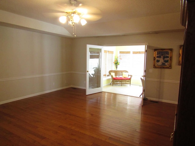 empty room with ceiling fan, dark wood-type flooring, and vaulted ceiling