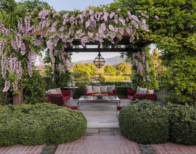 view of community featuring a pergola, a patio area, an outdoor living space, and a mountain view