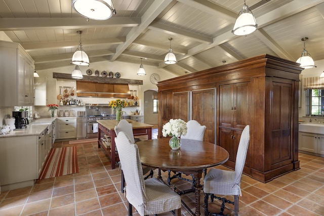 dining space with vaulted ceiling with beams, light tile patterned flooring, and sink