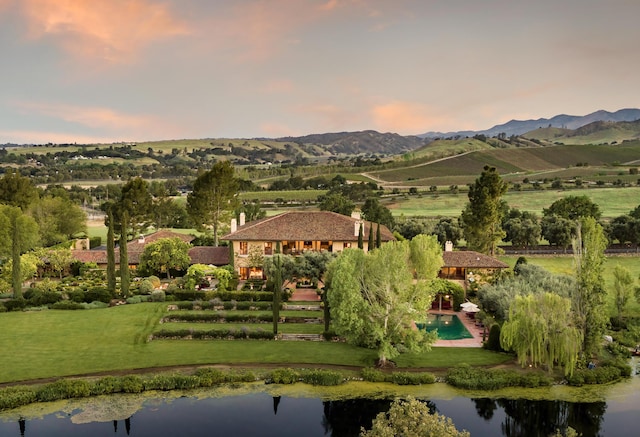 aerial view at dusk featuring a water and mountain view