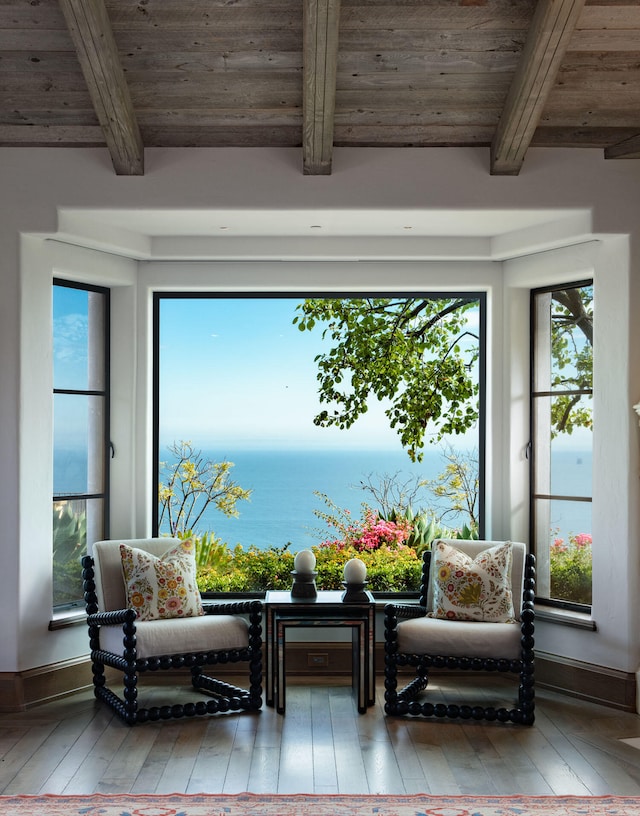 sitting room with light hardwood / wood-style floors, wood ceiling, a water view, and beamed ceiling