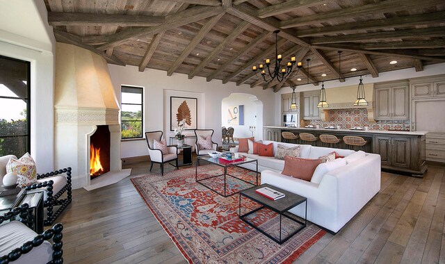 living room with a chandelier, beamed ceiling, wooden ceiling, and dark hardwood / wood-style flooring