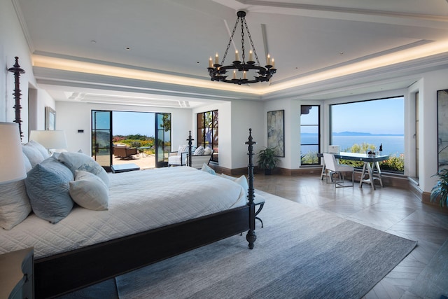 bedroom featuring multiple windows, a water view, a chandelier, and a raised ceiling