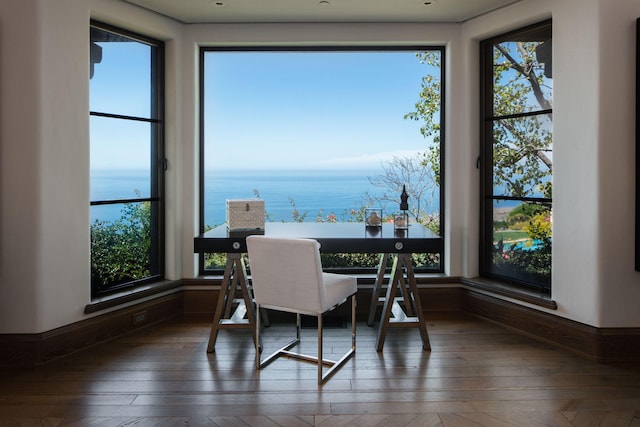 dining space with plenty of natural light, dark wood-type flooring, and a water view