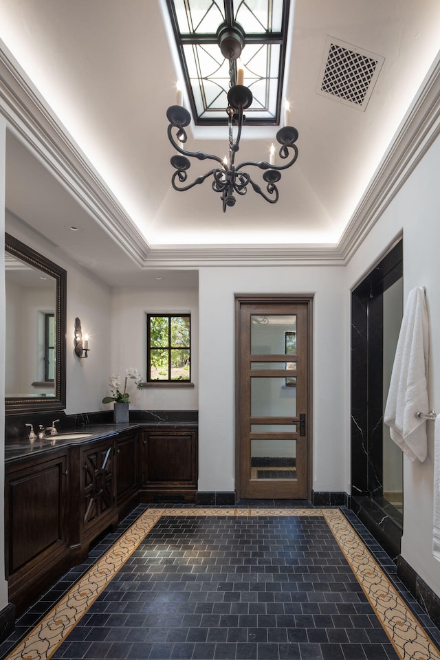 bathroom with vanity, a skylight, a notable chandelier, and a tray ceiling