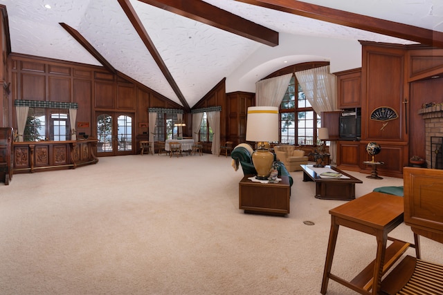 carpeted living room with beam ceiling, wood walls, a wealth of natural light, and french doors