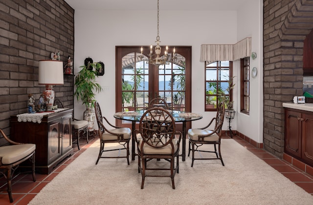 tiled dining space with an inviting chandelier, brick wall, and plenty of natural light