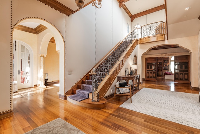 entryway featuring ornamental molding, wood-type flooring, and a high ceiling