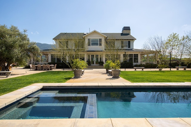 rear view of property with a swimming pool with hot tub, a yard, and a patio area