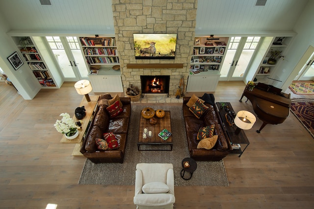 living room with a fireplace, french doors, a healthy amount of sunlight, and light wood-type flooring