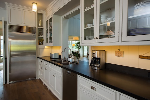 kitchen featuring dark wood-type flooring, built in fridge, white cabinets, dishwasher, and sink