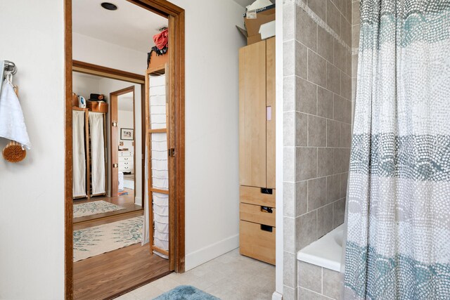 bathroom with baseboards, tiled shower / bath combo, and tile patterned floors