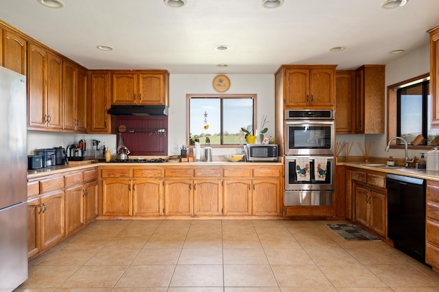 kitchen with light countertops, stainless steel appliances, under cabinet range hood, a sink, and light tile patterned floors
