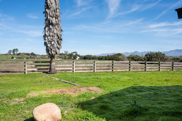 view of yard featuring a mountain view, fence, and a rural view