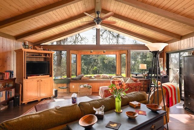 living area featuring vaulted ceiling with beams, wooden walls, wood finished floors, and a ceiling fan