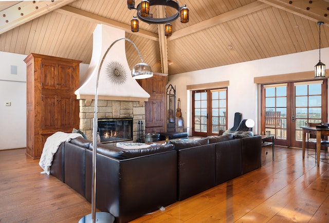 living room with a stone fireplace, hardwood / wood-style floors, high vaulted ceiling, and french doors